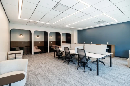 Modern coworking space featuring ergonomic chairs and collaborative workstations, complemented by cozy seating areas and stylish lighting. The design emphasizes functionality and comfort with a neutral color palette and ample natural light.