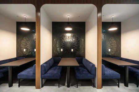 Modern dining area featuring cozy blue upholstered seating with sleek tables and decorative wall art, ideal for intimate gatherings or collaborative work.