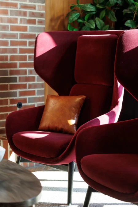 Deep red armchair with a brown leather pillow.