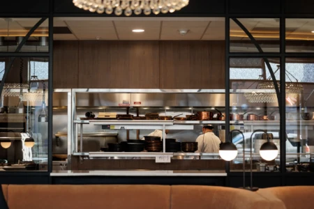 Open kitchen with chefs, copper cookware, and modern decor.