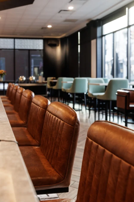 Brown leather chairs lined along a modern bar counter.
