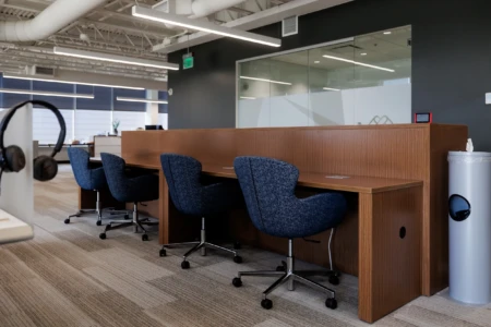 Workstations with blue chairs and wood paneling in office.