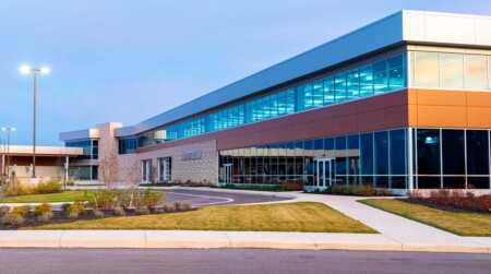 Modern commercial building exterior featuring large windows, a stone facade, and landscaped surroundings, ideal for business operations and client engagement.